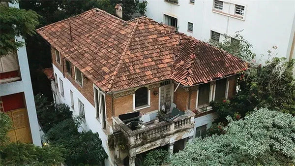 Overgrown greenery surrounds a decaying house in "Abandoned: Woman in Decaying Home".