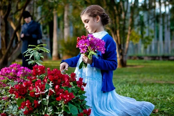 A girl picks vibrant flowers in a garden from "Através da Sombra".