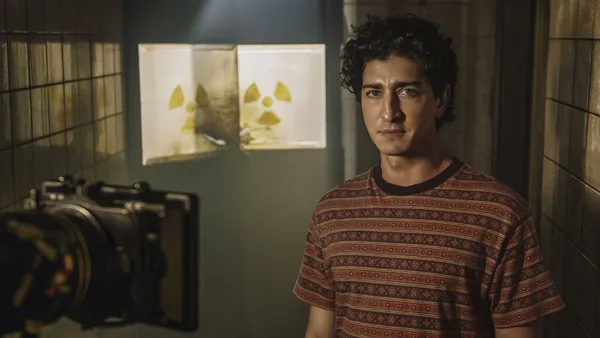 A character in "Emergência Radioativa" stands near radioactive signs in a room.