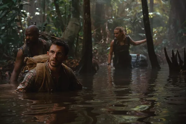 Characters in "Jurassic World Rebirth" wading through water in a dense jungle.