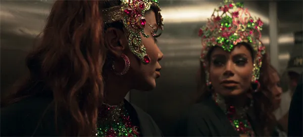 Women in elaborate headpieces are in an elevator in "Larissa: O Outro Lado de Anitta".