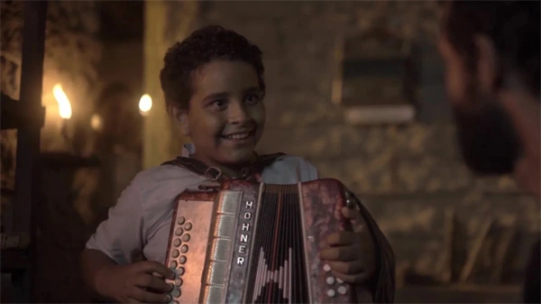 Boy with accordion smiles at night in Luiz Gonzaga Légua Tirana.