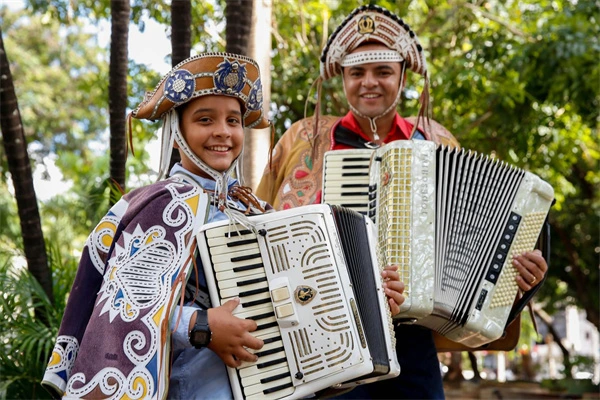 Two people in traditional costumes hold accordions in Luiz Gonzaga Légua Tirana.