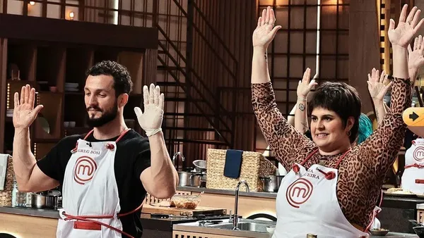 Contestants of "MasterChef Creators" joyfully raising their hands in the kitchen.