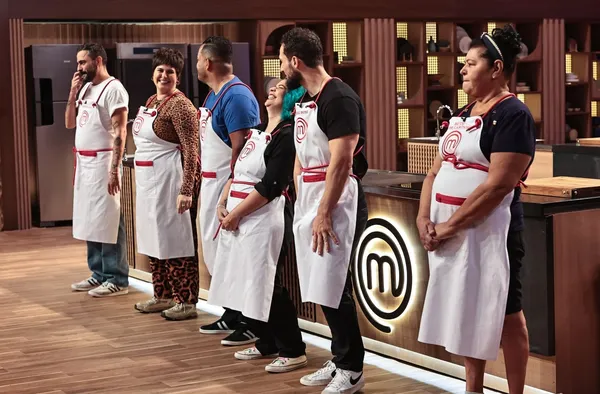 Contestants of "MasterChef Creators" lined up in the kitchen workspace.