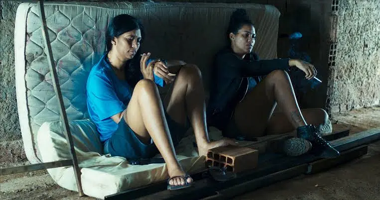 Two women sitting on a mattress, appearing contemplative in "Mato seco em chamas".