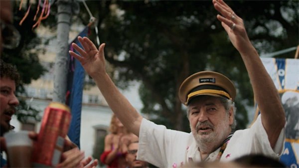 Man interacts with crowd on the street in Moacyr Luz, O Embaixador Dessa Cidade.