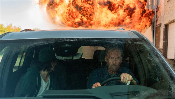 Two people in a car escape an explosion in Anônimo 2.