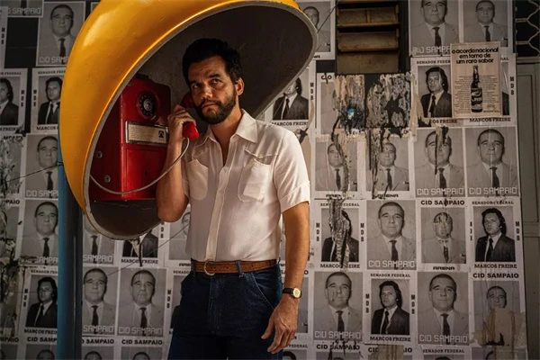 A secret agent uses a retro phone booth surrounded by campaign posters.