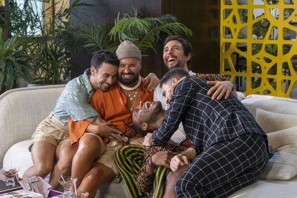 Four men hug and laugh heartily on a couch in Queer Eye Brazil.