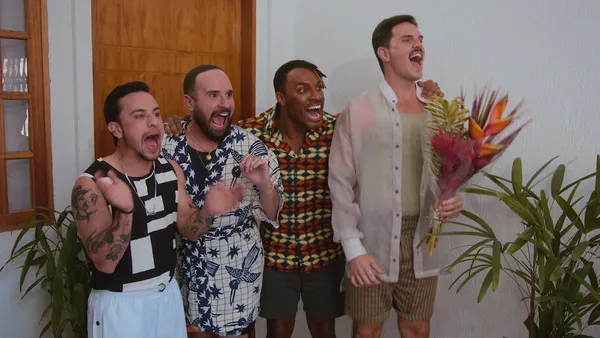 Four men cheer excitedly indoors in Queer Eye Brazil.