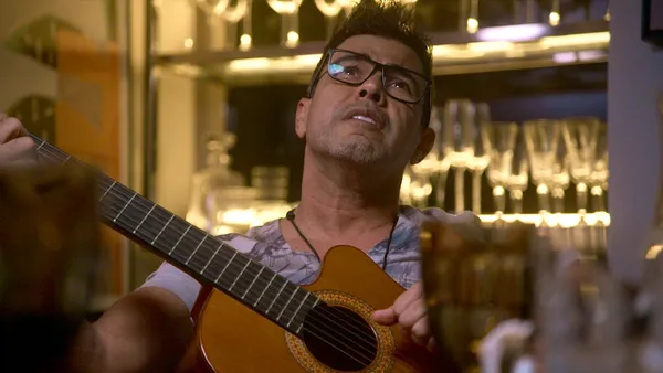 Man plays guitar in a cozy space in The Family That Sings Together: The Camargos.