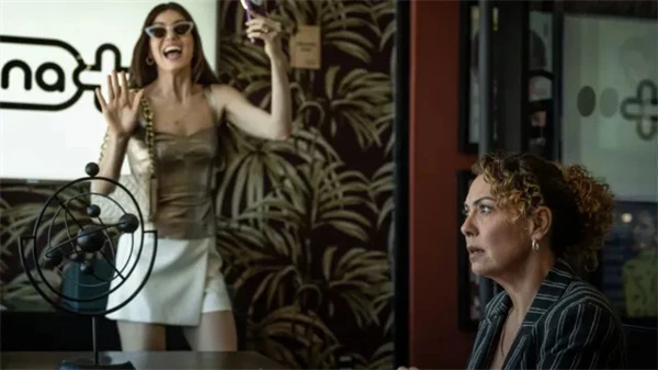 A lively woman celebrates while a serious woman looks on in Uma Mulher Sem Filtro’s office