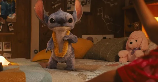 Stitch wears a lei while standing on a bed in "Lilo & Stitch (2025)".