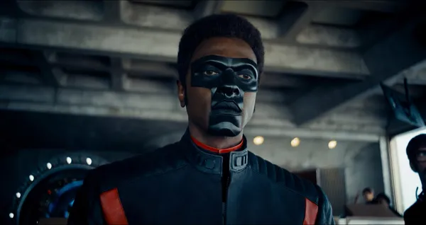A masked character stands in an indoor setting in "Superman (2025)".